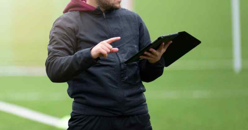 A sports coach uses a tablet to review performance data and provide real-time feedback during a training session.
