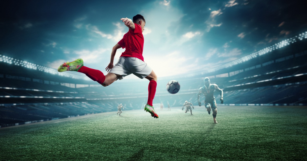 A soccer player in a red uniform leaps to kick the ball as virtual opponents approach in a brightly lit stadium.