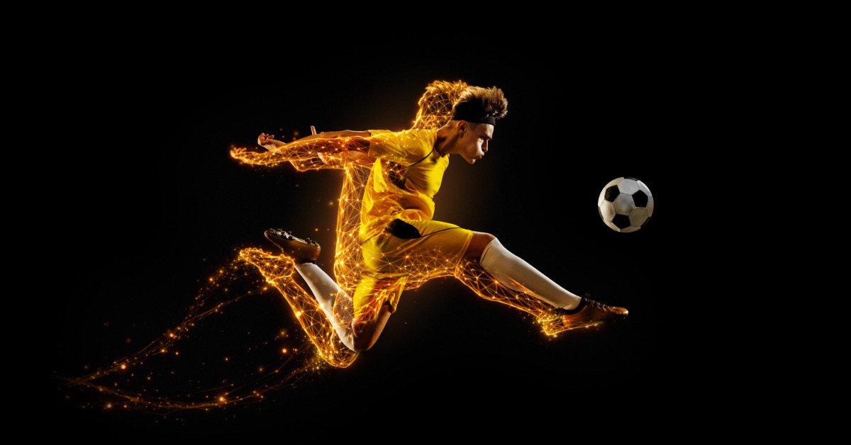 A soccer player in a yellow uniform kicking a ball with glowing orange light trails against a black background.